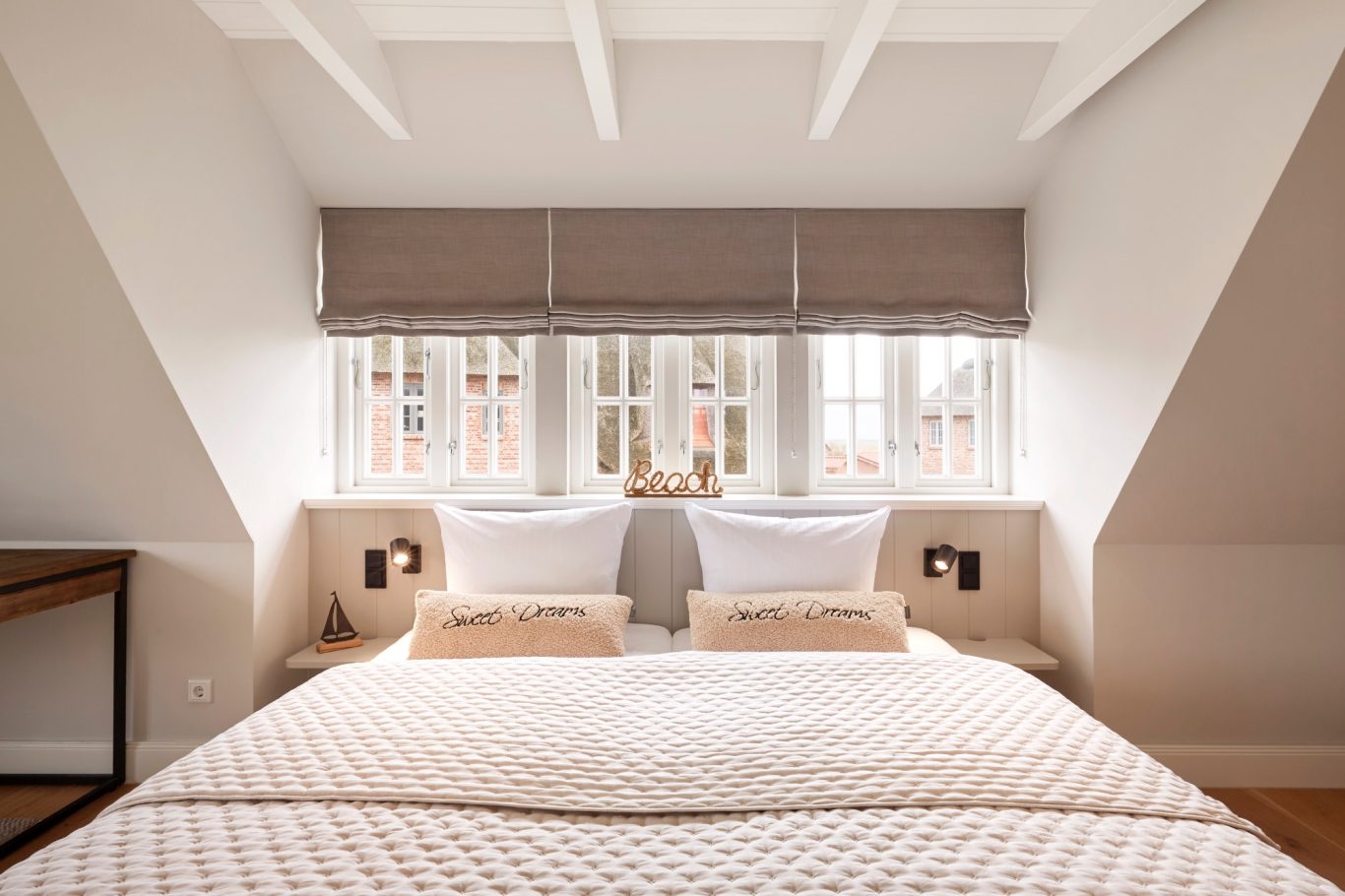 Schlafzimmer mit Doppelbett, Fenster und modernen Möbeln unter einem Dachschräge.