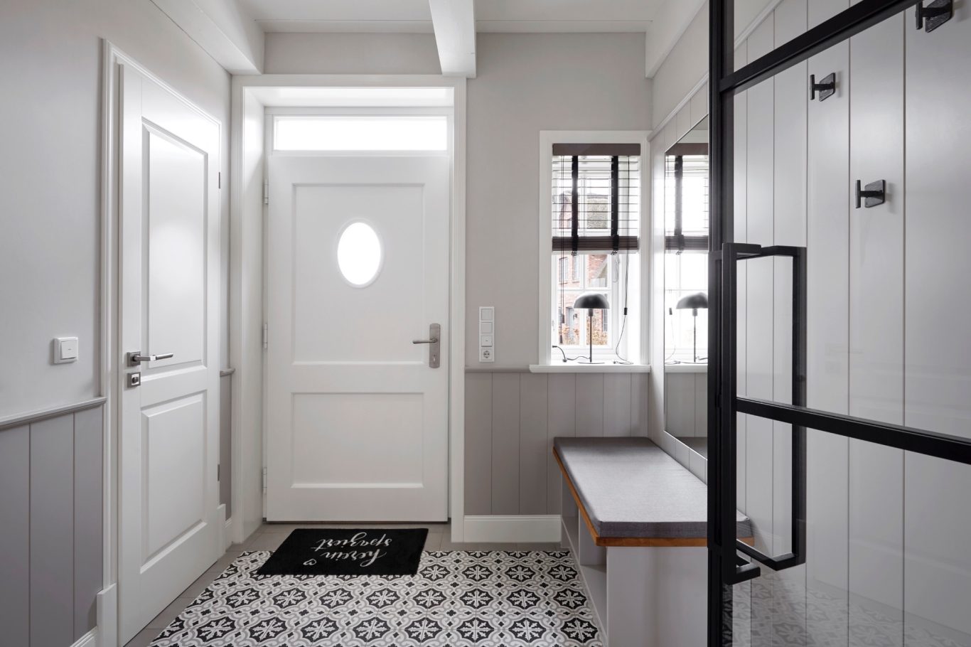 Moderner Eingangsbereich mit ovalem Fenster, Holzbank und Glaswand.