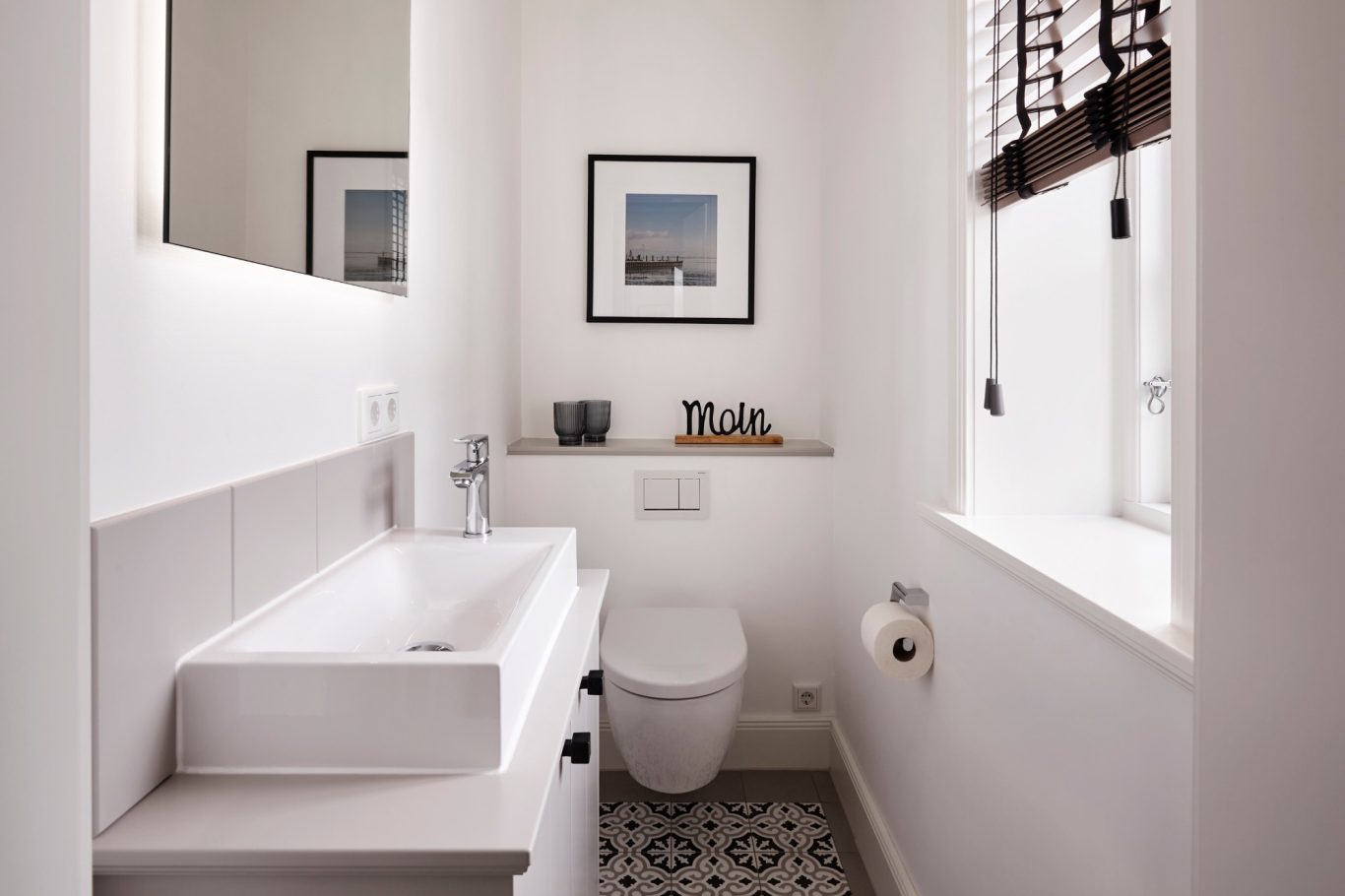 Heller Badezimmer mit Waschbecken, WC, kunstvollem Bild und dekorativen Accessoires.