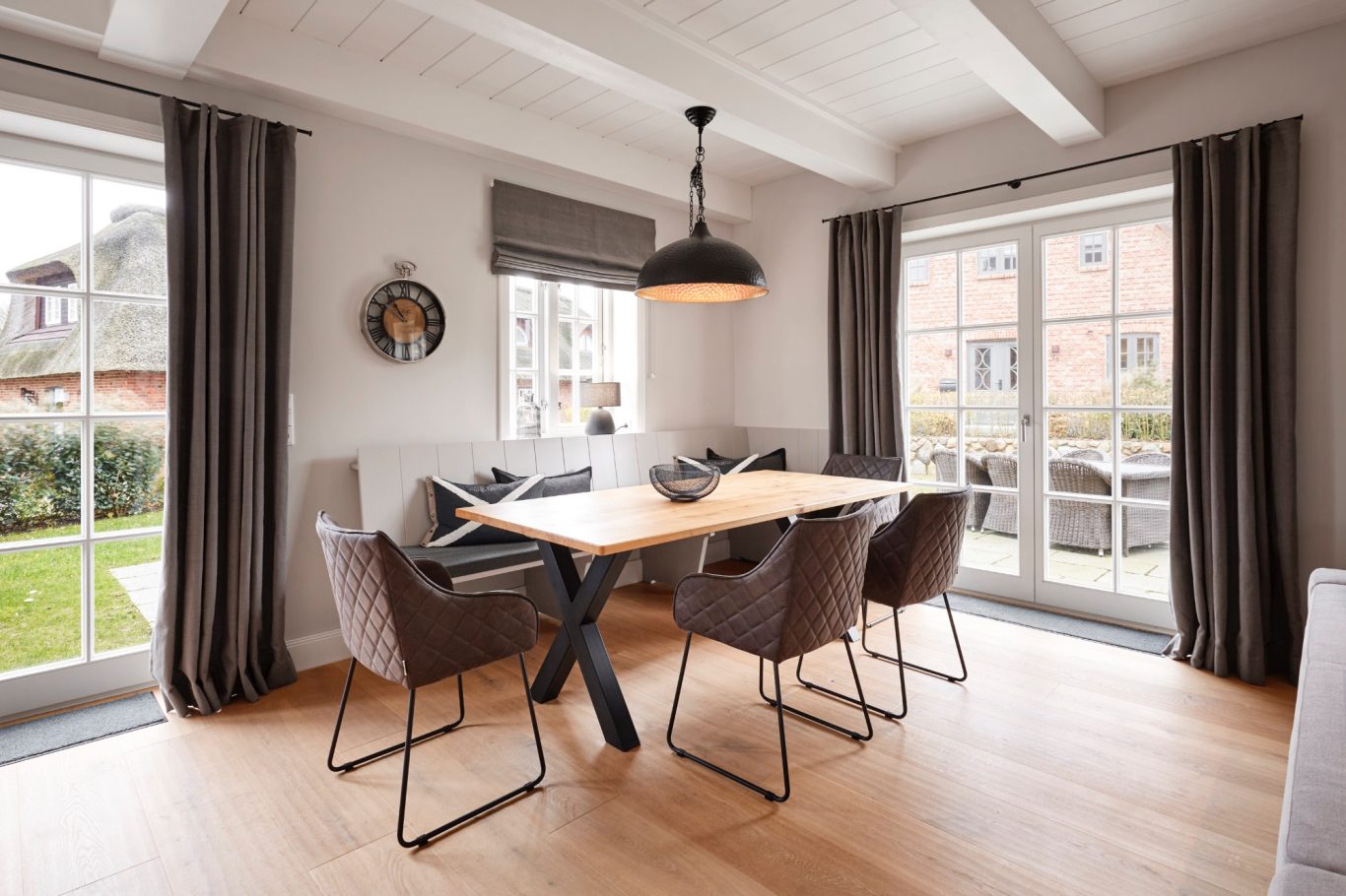 Heller Essbereich mit Holzstisch, Stühlen, Pflanzen und einer großen Lampe.