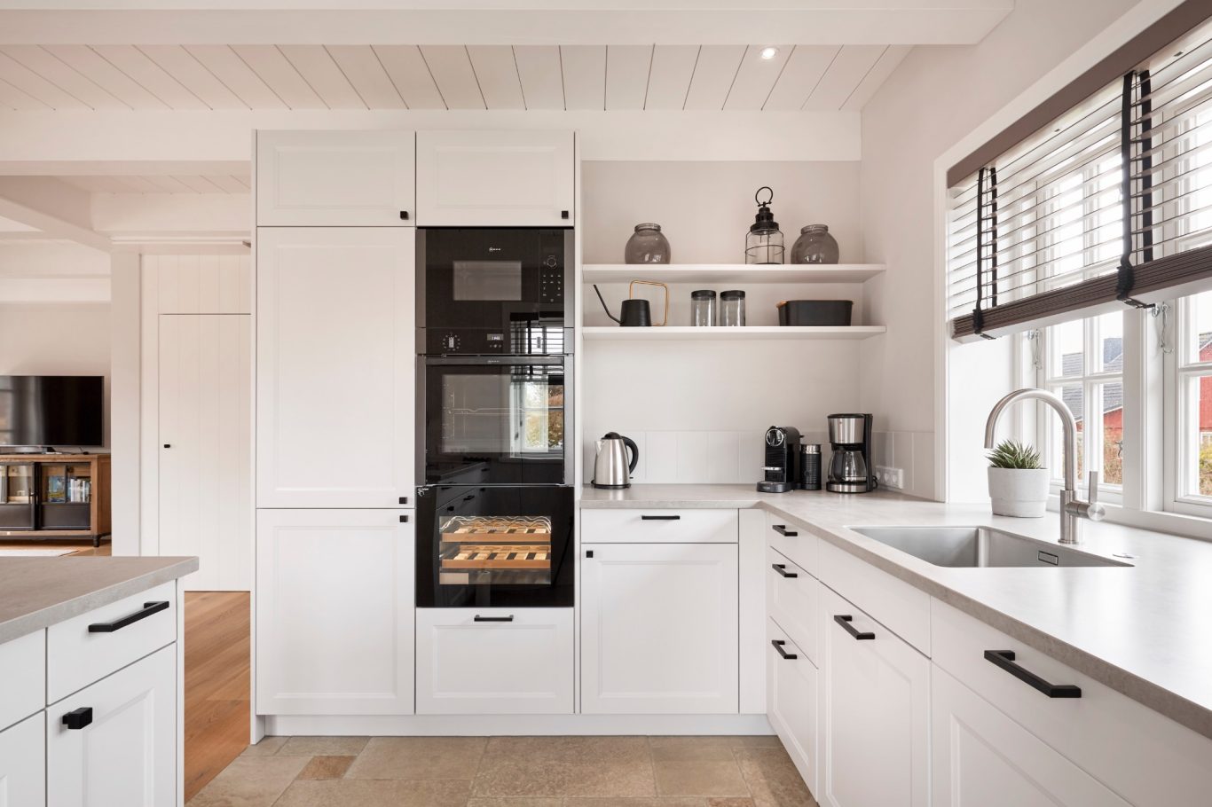 Moderne Küche mit weißen Schränken, Backofen, Spüle und Küchenmaschinen.