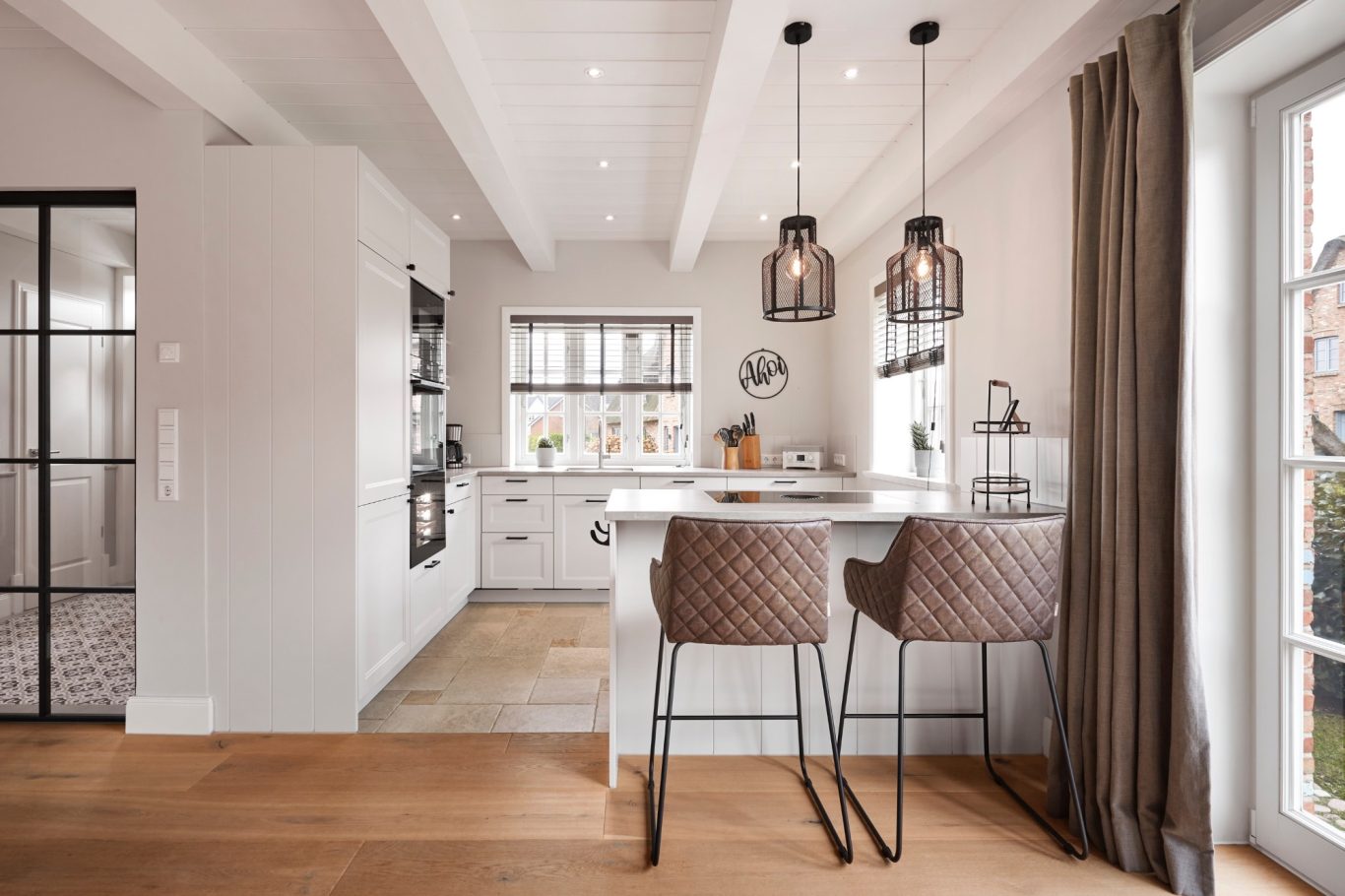 Moderne, helle Küche mit Barhockern, Holzfußboden und großen Fenstern.