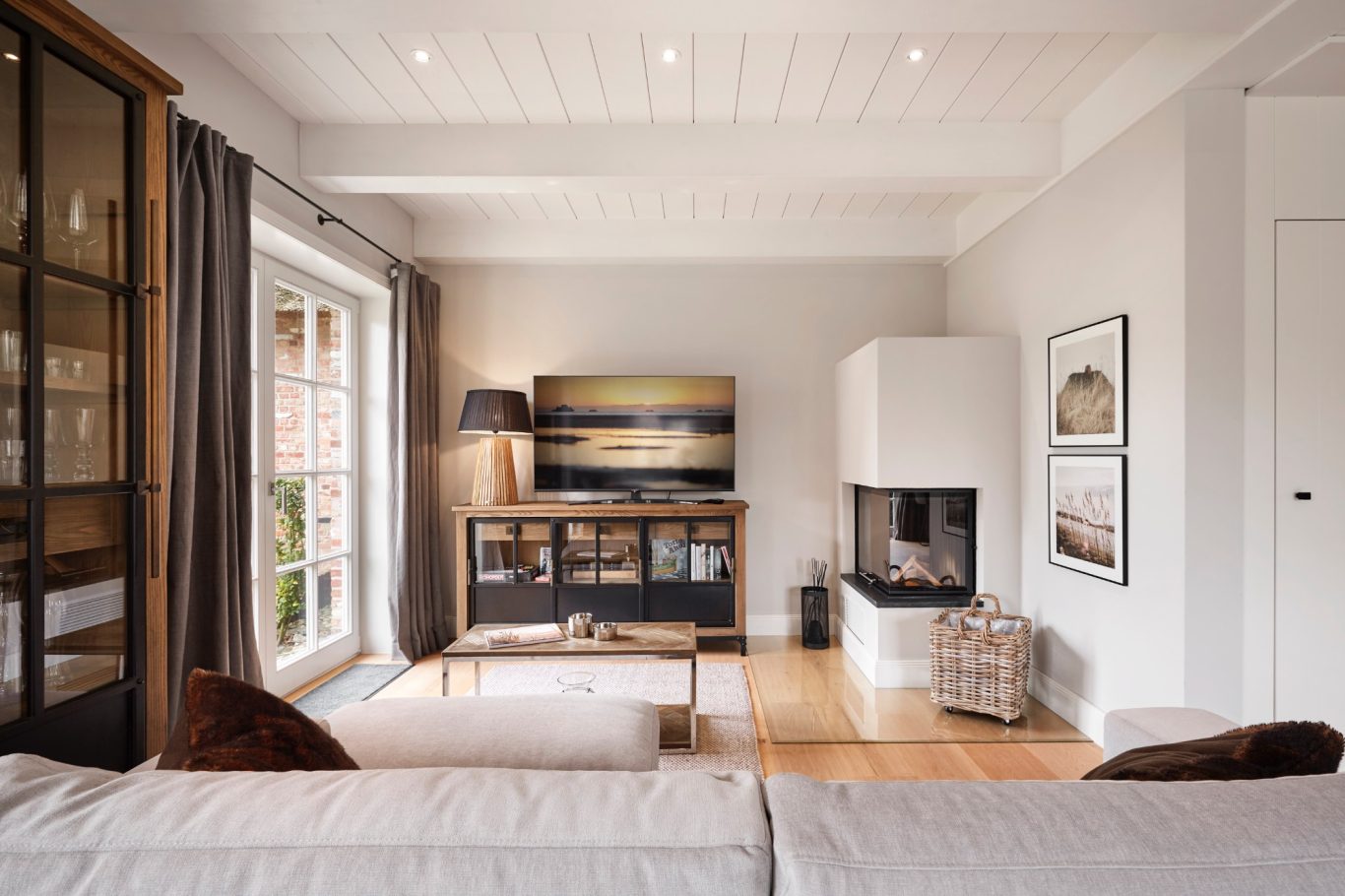 Modern Wohnzimmer mit Fernseher, Kamin, Holztisch und gemütlicher Dekoration.