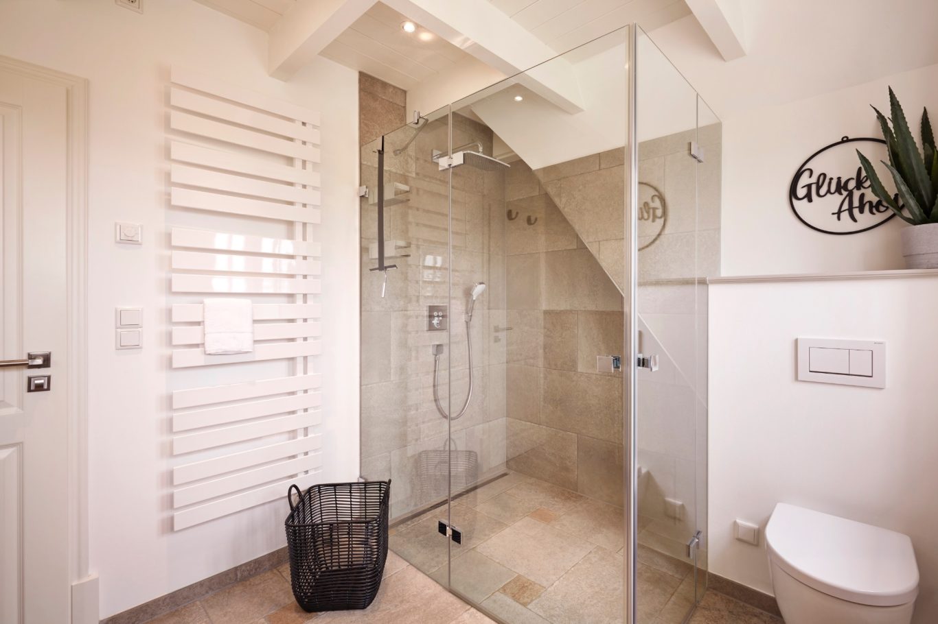 Moderne Badezimmer mit Dusche, WC und Pflanzen. Helle Fliesen, Glasabtrennung, Wäschekorb.
